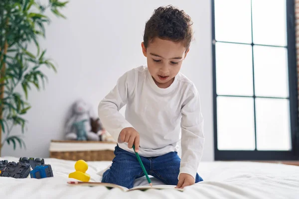 stock image Adorable hispanic boy preschool student sitting on bed drawing on notebook at bedroom