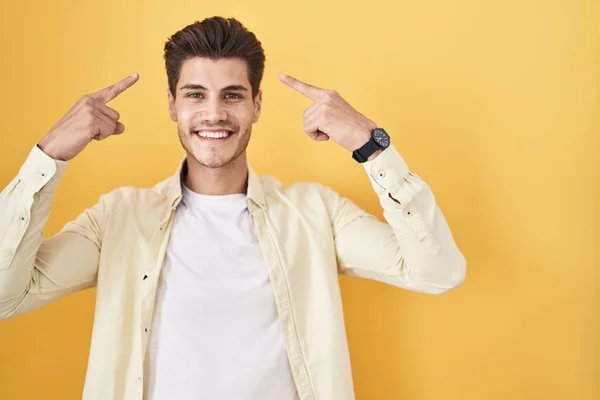 Young Hispanic Man Standing Yellow Background Smiling Pointing Head Both — Fotografia de Stock