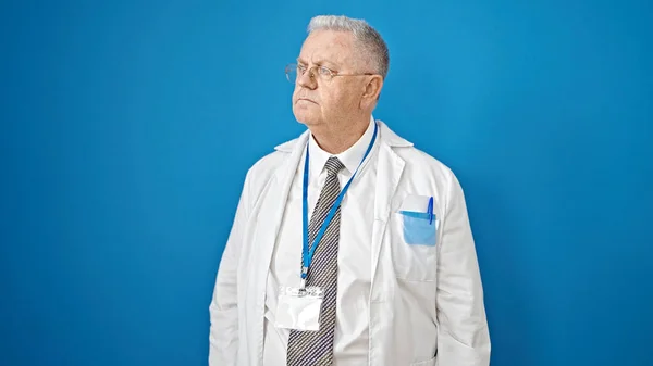 Középkorú Ősz Hajú Férfi Orvos Áll Komoly Kifejezés Izolált Kék — Stock Fotó