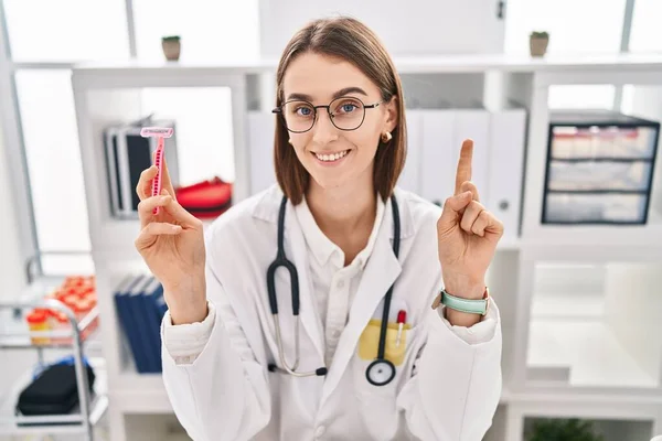 Young Caucasian Doctor Woman Holding Razor Smiling Idea Question Pointing — Stock Photo, Image