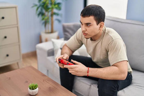 年轻人坐在家里的沙发上玩电子游戏 — 图库照片