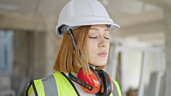 Young blonde woman architect standing with relaxed expression at construction site