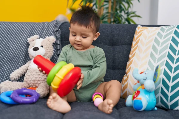 stock image Adorable hispanic boy playing with hoops game sitting on sofa at home