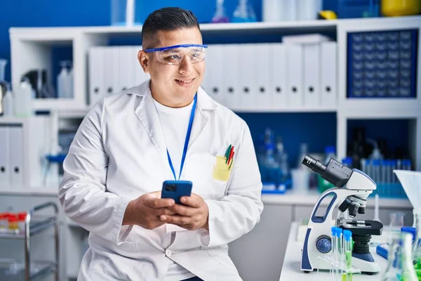 Νεαρός Λατίνος Επιστήμονας Χαμογελώντας Αυτοπεποίθηση Χρησιμοποιώντας Smartphone Στο Εργαστήριο — Φωτογραφία Αρχείου