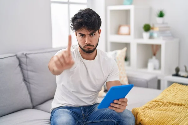 Hispanic Man Beard Using Touchpad Sitting Sofa Pointing Finger Angry — Stock Photo, Image