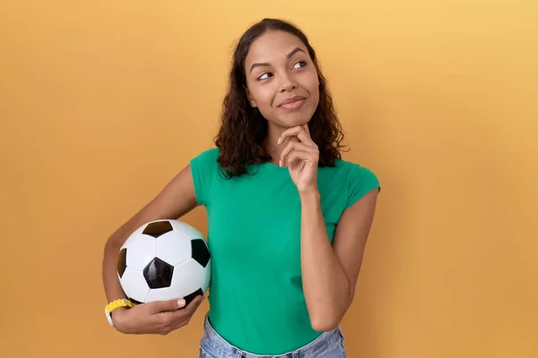 若いヒスパニック系の女性の質問については 集中的な表現を考えて顎に手でボールを保持 笑顔で思いやりのある顔 疑わしい概念 — ストック写真