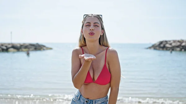 年轻的金发女游客穿着比基尼在海滩上飞吻 — 图库照片