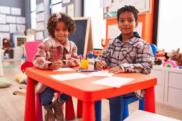 愛らしいアフリカ系アメリカ人の少年少女幼稚園の机の上に座って紙の上に絵を描く — ストック写真