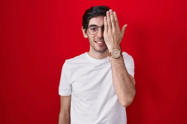 Νεαρός Ισπανόφωνος Στέκεται Πάνω Από Κόκκινο Φόντο Καλύπτει Ένα Μάτι — Φωτογραφία Αρχείου