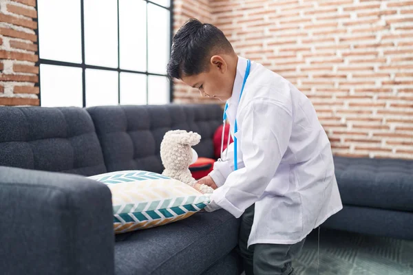 Uroczy Latynoski Chłopiec Mundurze Lekarza Badający Pluszowego Misia Domu — Zdjęcie stockowe