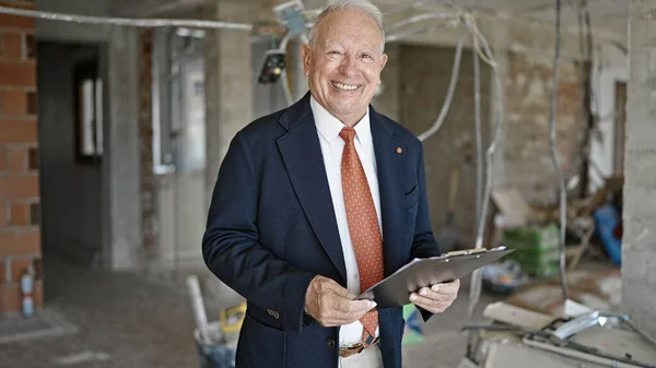 stock image Senior grey-haired man real state agent smiling confident holding clipboard at construction site