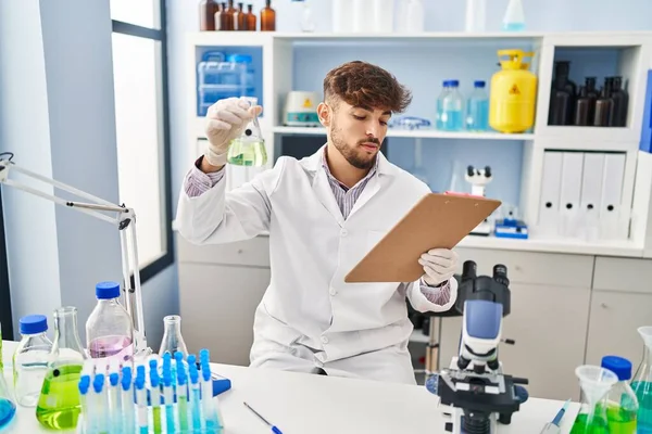 Young Arab Man Scientist Measuring Liquid Reading Report Laboratory — Stockfoto