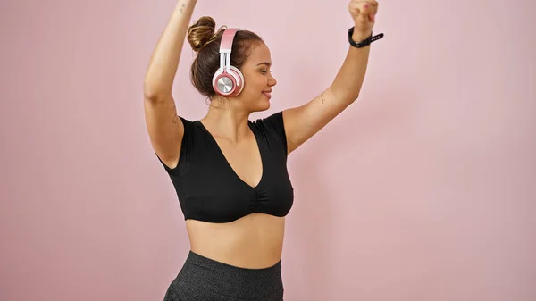 stock image Young beautiful hispanic woman wearing sportswear listening to music dancing over isolated pink background