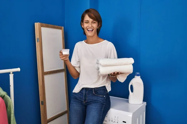 きれいな洗濯を持っているブルネットの女性は笑顔と笑いハードアウト大声で面白いクレイジー冗談ので — ストック写真