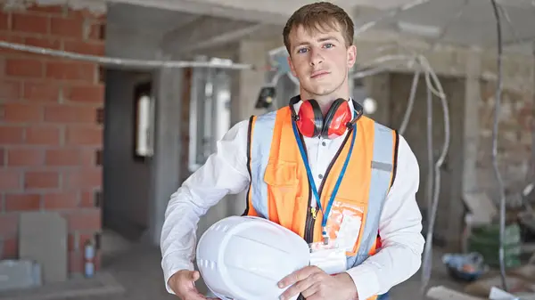 年轻的高加索人建筑师站在建筑工地上 头戴硬礼帽 表情轻松 — 图库照片