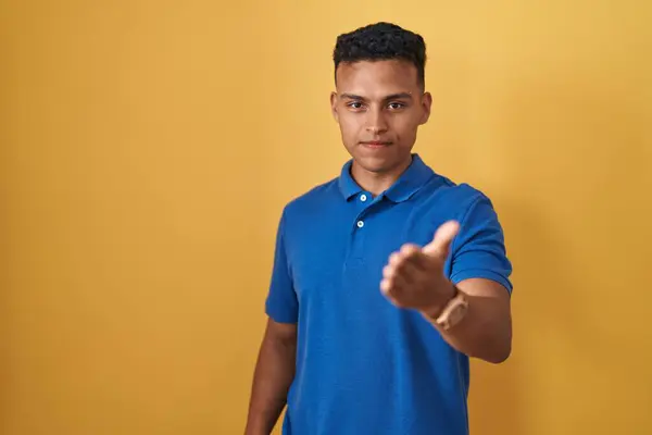 Joven Hombre Hispano Pie Sobre Fondo Amarillo Sonriente Alegre Ofreciendo — Foto de Stock