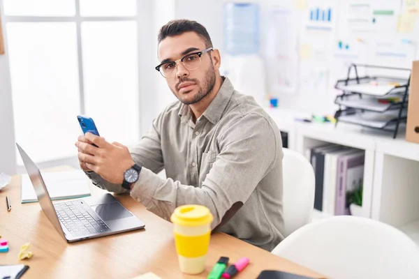 Young Hispanic Man Business Worker Using Laptop Talking Smartphone Office —  Fotos de Stock