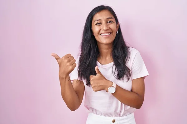 Young Hispanic Woman Standing Pink Background Pointing Back Hand Thumbs — Stock fotografie