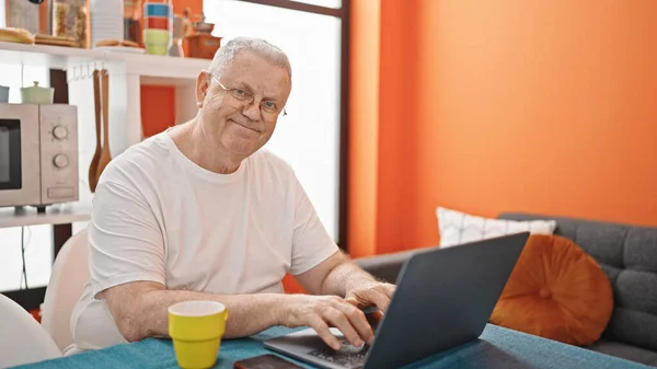 中年白发男子在饭厅用笔记本电脑微笑 — 图库照片