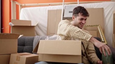 Genç İspanyol adam gülümsüyor. Yeni evdeki karton kutuyu açtığından emin.