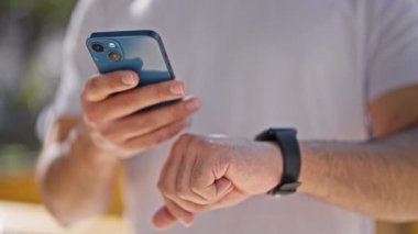 Parkta akıllı telefon ve akıllı telefon kullanan genç bir latin.