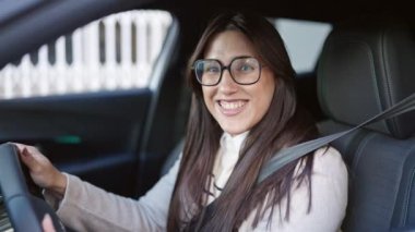 Genç, güzel İspanyol kadın gülümsüyor. Sokakta kendine güvenen araba kullanıyor.