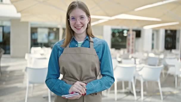 Νεαρή Ξανθιά Σερβιτόρα Χαμογελαστή Αυτοπεποίθηση Κρατώντας Σημειωματάριο Στη Βεράντα Της — Αρχείο Βίντεο