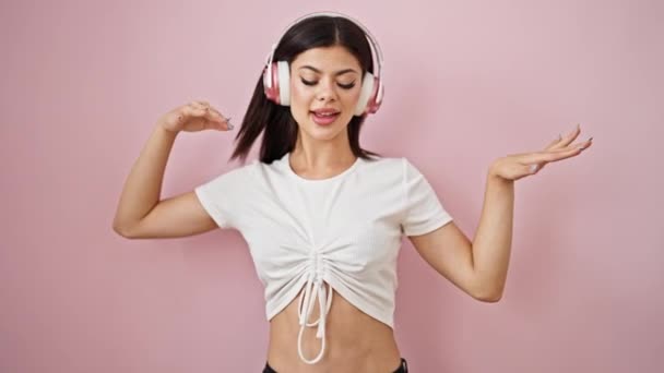 Молода Біла Жінка Слухає Музику Танцює Над Ізольованим Рожевим Тлом — стокове відео