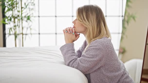 年轻的金发女人靠在床上 在卧室祈祷 — 图库视频影像