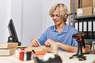 Genç sarışın iş adamı ofiste paket hazırlıyor.