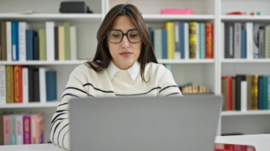 Kütüphanede dizüstü bilgisayar kullanan güzel İspanyol bir kız öğrenci.