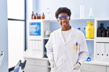 African american woman wearing scientist uniform standing at laboratory