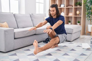 Young hispanic man training yoga at home