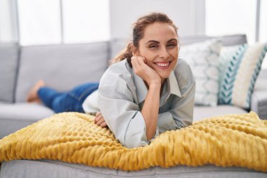 Young woman smiling confident lying on sofa at home