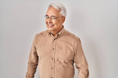 Hispanic senior man wearing glasses winking looking at the camera with sexy expression, cheerful and happy face. 
