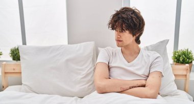 Genç, İspanyol, mutsuz bir adam yatak odasında oturuyor.