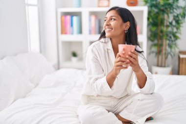 Genç, güzel, İspanyol bir kadın. Yatak odasında bir fincan kahve içiyor.