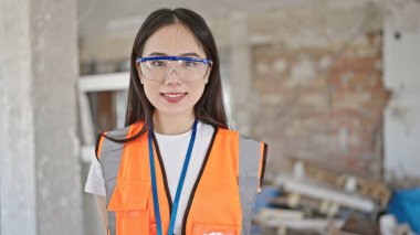 İnşaat alanında kendinden emin gülümseyen genç Çinli kadın inşaatçı.