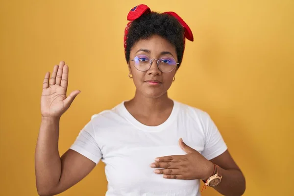 Ung Afrikansk Amerikansk Kvinde Stående Gul Baggrund Sværger Med Hånd - Stock-foto