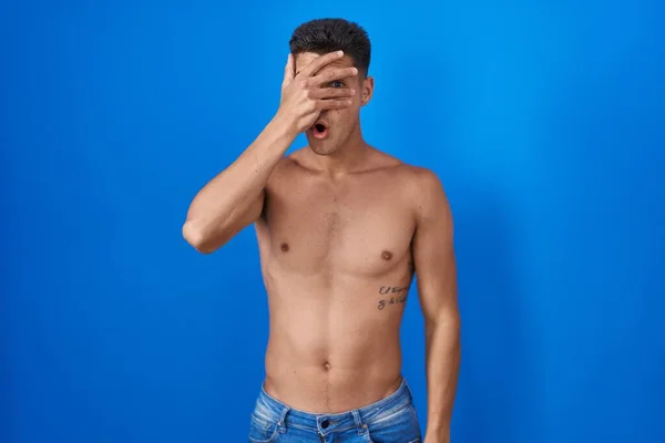 Joven Hombre Hispano Pie Sin Camisa Sobre Fondo Azul Asomándose — Foto de Stock