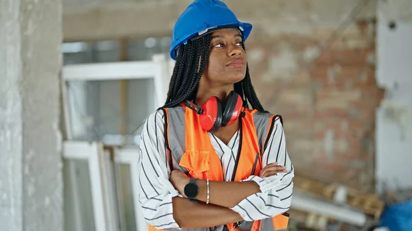 アフリカ系アメリカ人女性の建設現場で腕を組んで立ってジェスチャーや真剣な表情を交差 — ストック写真