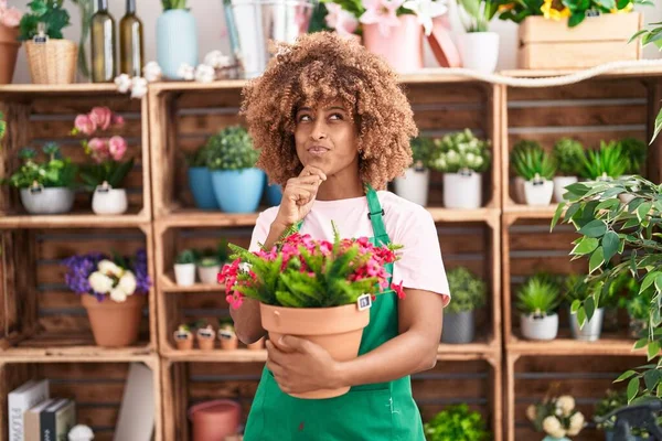 Mladá Hispánka Kudrnatými Vlasy Pracující Květinářství Držící Rostlinu Vážnou Tvář — Stock fotografie