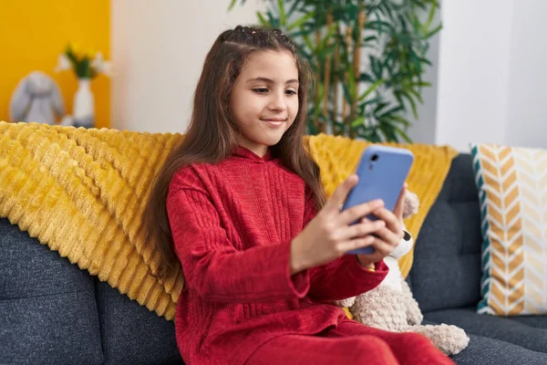 可爱的他的恐慌女孩坐在家里的沙发上用智能手机 — 图库照片