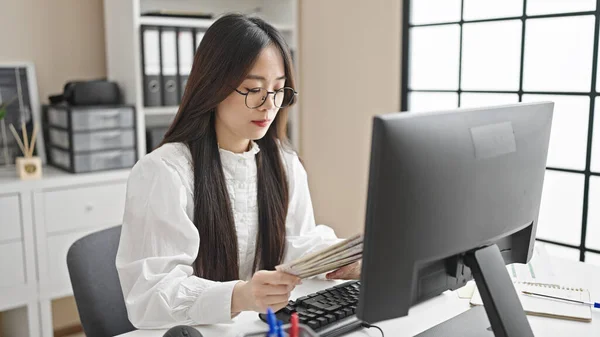 若い中国の女性のビジネス労働者はオフィスでドルを数えるコンピュータを使用して — ストック写真