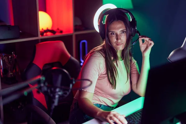 Stock image Young beautiful hispanic woman streamer sitting on table with serious expression at gaming room