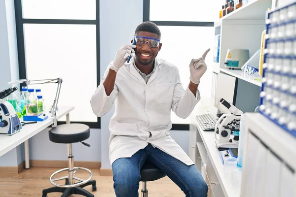 アフリカ系アメリカ人の男性科学者の研究室で働いている携帯電話で笑顔側に手と指を指して幸せ — ストック写真