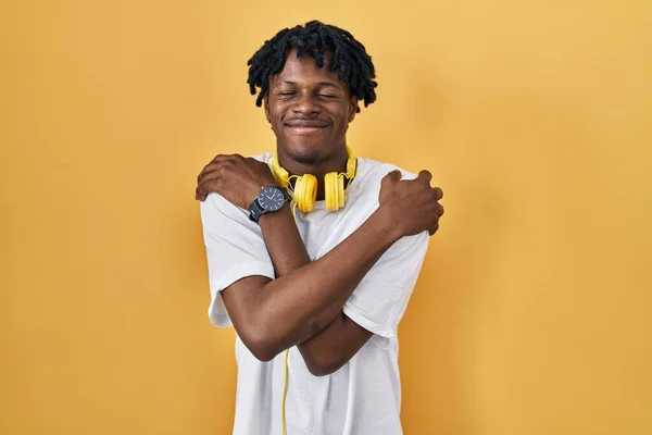 Young African Man Dreadlocks Standing Yellow Background Hugging Oneself Happy — Stock Photo, Image