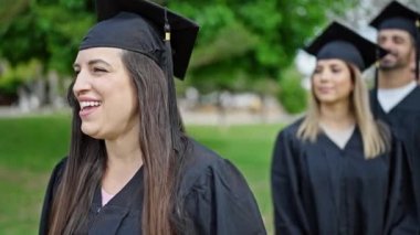 Bir grup insan üniversite kampüsünde gülerek mezun oldu.
