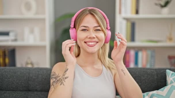 年轻的金发女人在家一边听音乐一边掏出耳机 — 图库视频影像
