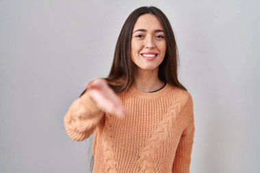 Beyaz arka planda duran esmer bir kadın selamlama ve hoş geldin demek için dostça bir şekilde tokalaşıyor. başarılı iş. 